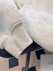 Close-up of light grey hoodie sleeve showing its ribbed cuff and heathered fabric