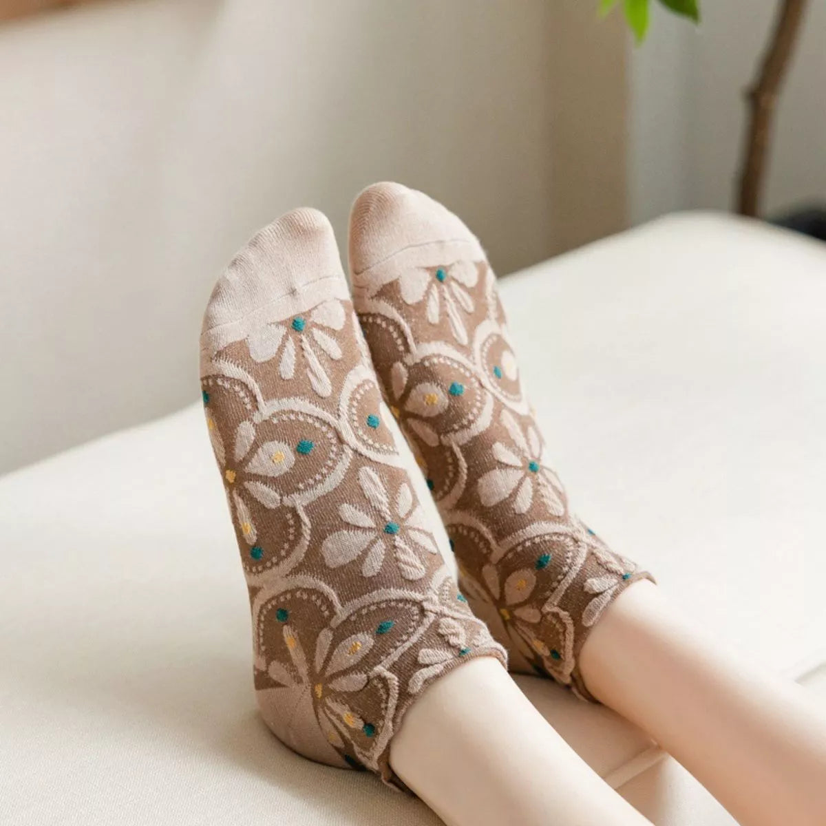 Brown floral ankle socks with beige toes shown on raised feet