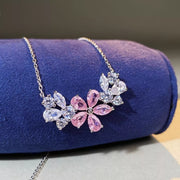 Blush pink and clear flower pendant necklace displayed on blue cushion