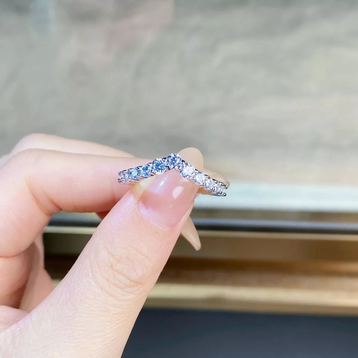 Close view of the V-shaped band with clear stones held between fingers.