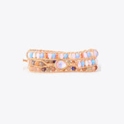 Three-wrap bracelet with pastel faceted beads, brown stones and a pink opal-shaped centerpiece on a light background