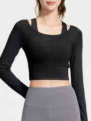 Front view of black cropped active top with layered scoop neckline over grey leggings