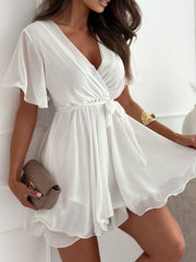 Model shows the white ruffled surplice dress and flutter sleeves