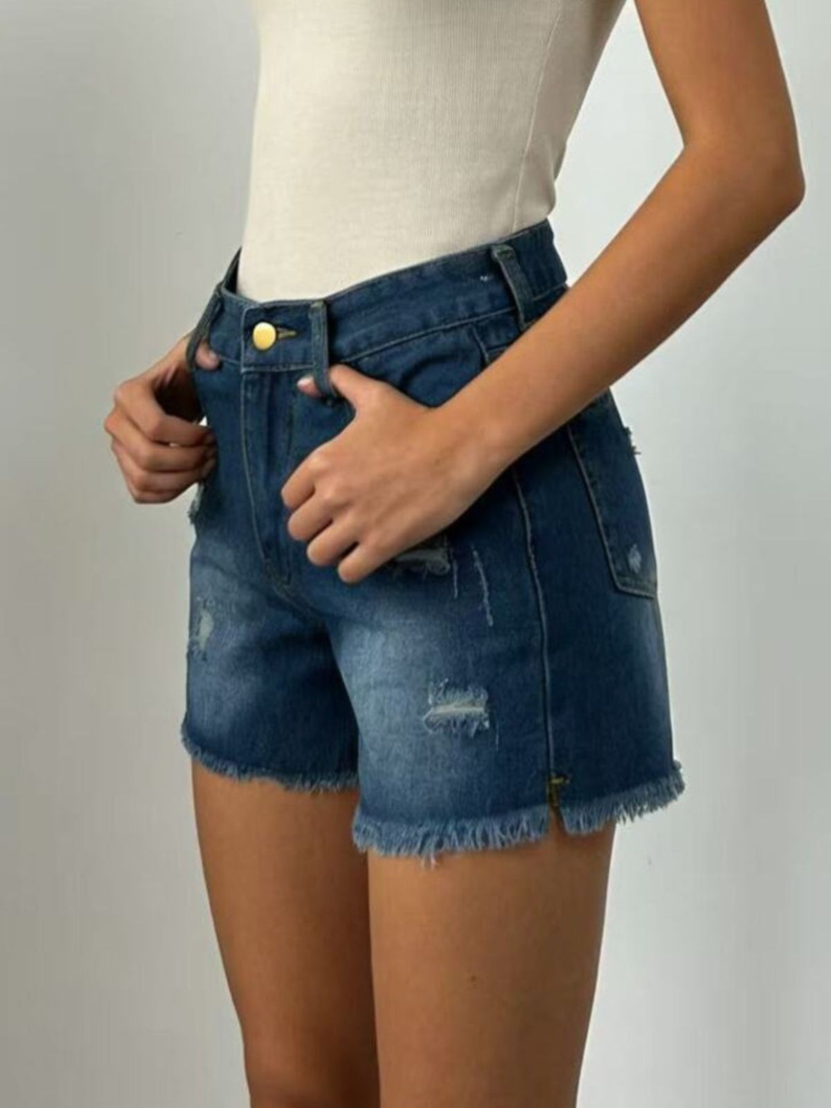 Back view of dark-wash denim shorts with frayed hems