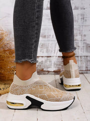 Rear and side view of beige slip-on trainers showing the gold-coloured heel detail