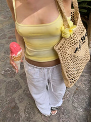 Yellow gradient cami with white pants and crochet bag