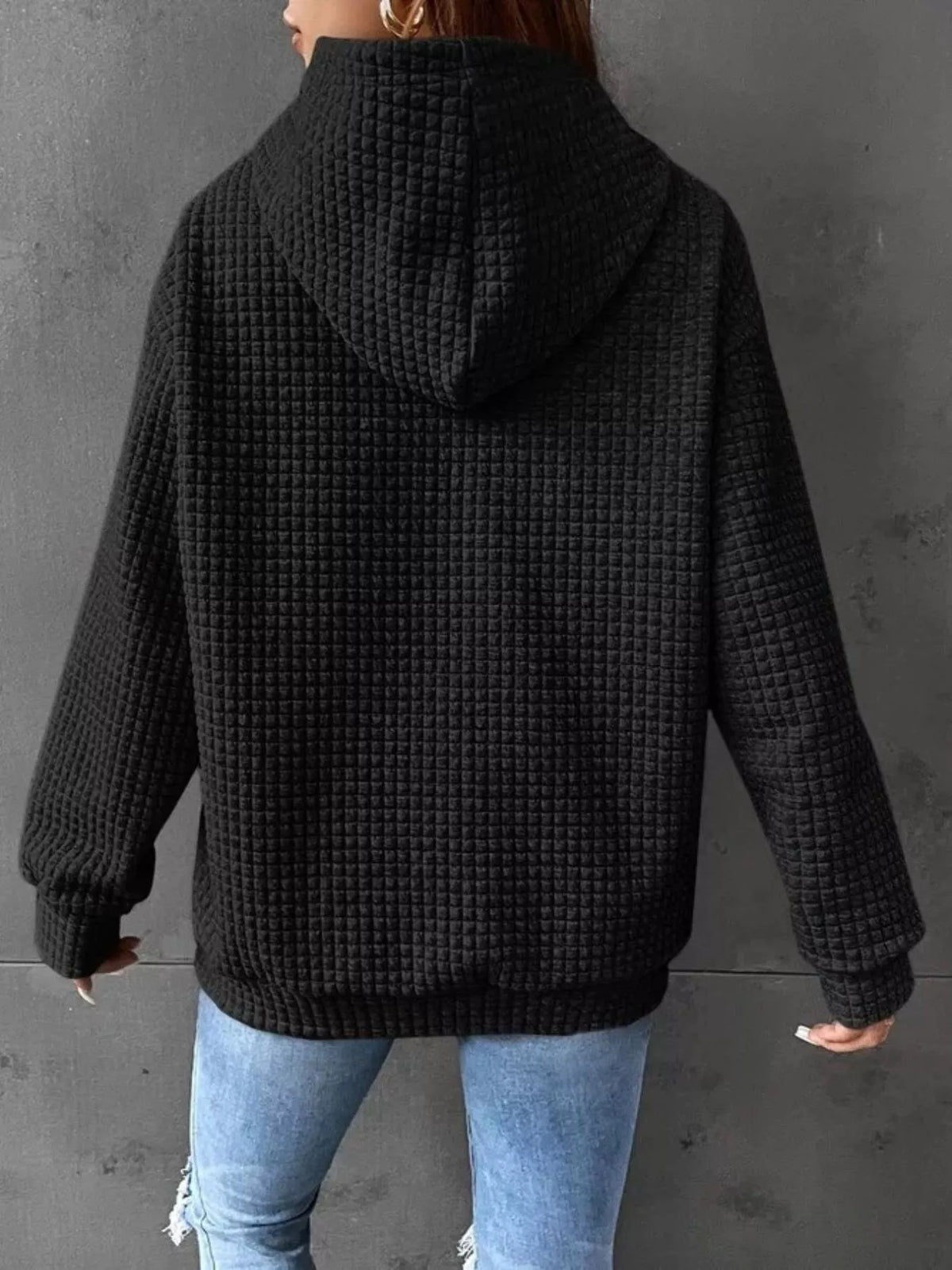 Back view of black textured hoodie with hood