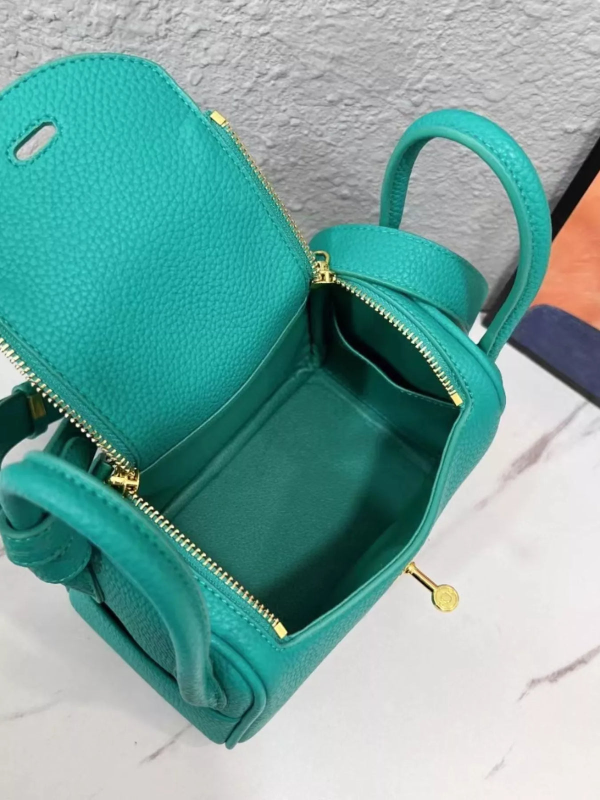 Open teal crossbody bag showing zippered compartments and interior