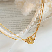 Close-up of layered pearl bracelet and round gold charm