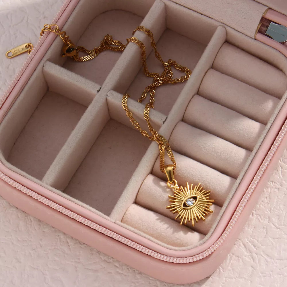 Gold-tone evil eye pendant necklace arranged in a jewelry case