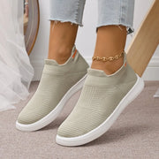 Beige knit slip-on shoes with white soles and orange heel accents, front view