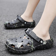 Black branch-print clogs with instep straps worn on pavement