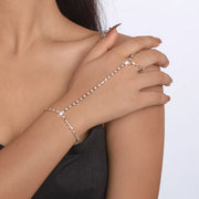 Hand wearing sparkling rhinestone bracelet connected to a finger ring