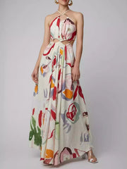 Front view of a white halter-neck maxi dress with a colorful abstract print and waist cut-outs.