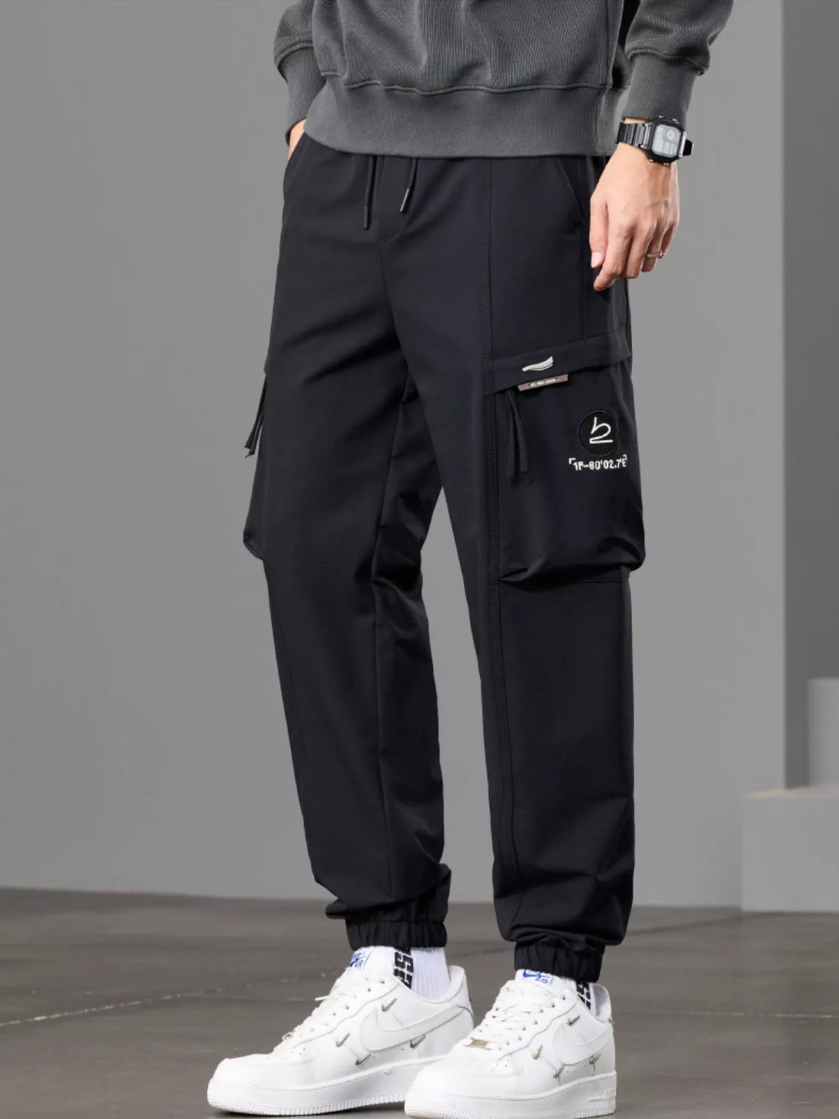 Angled rear view of black joggers showing the back pocket and cargo pocket.