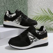 Pair of black sneakers with floral side panels and white soles
