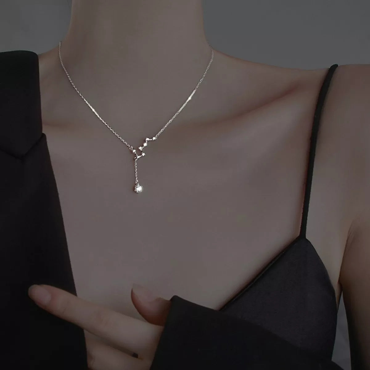 Close view of silver star necklace worn over a black top