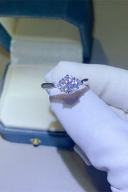Purple-stone ring held in a gloved hand beside a ring box