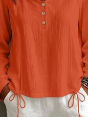 Close view of coral blouse front with buttons and drawstring waist detail.