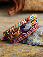 Angled view of the purple gemstone bracelet resting on a stone surface.