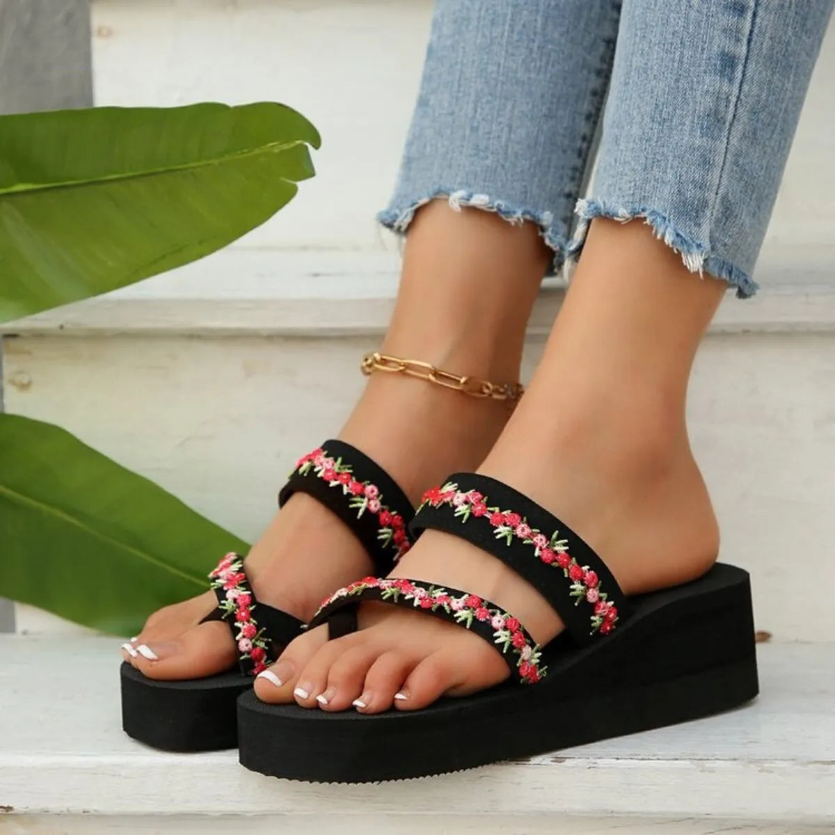 Black platform sandals with red and white floral trim across two straps, front view