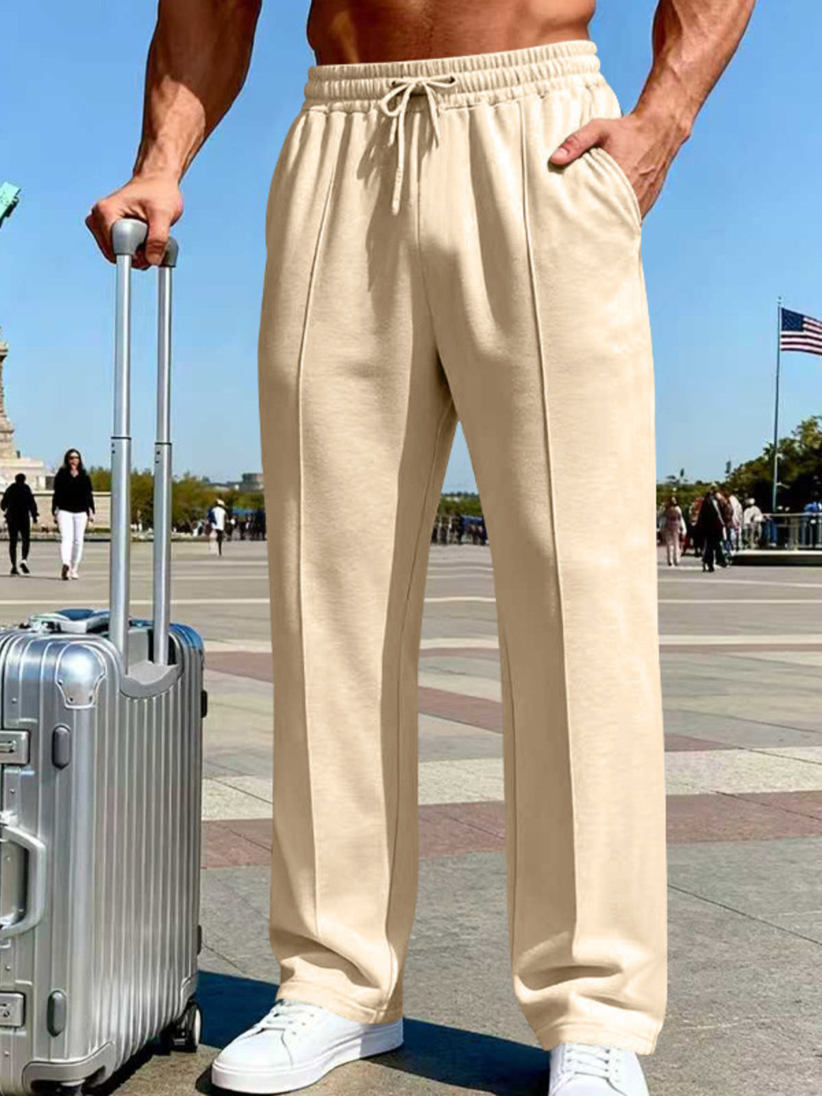 Front view of cream wide-leg drawstring pants beside a suitcase outdoors.