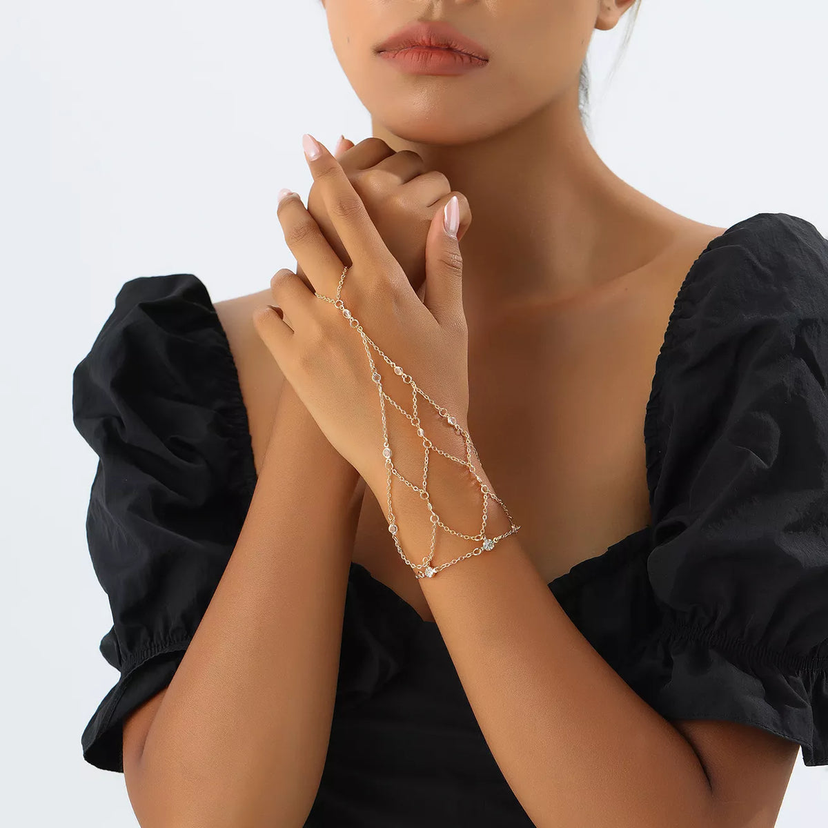 Gold-tone hand chain worn with a dark outfit