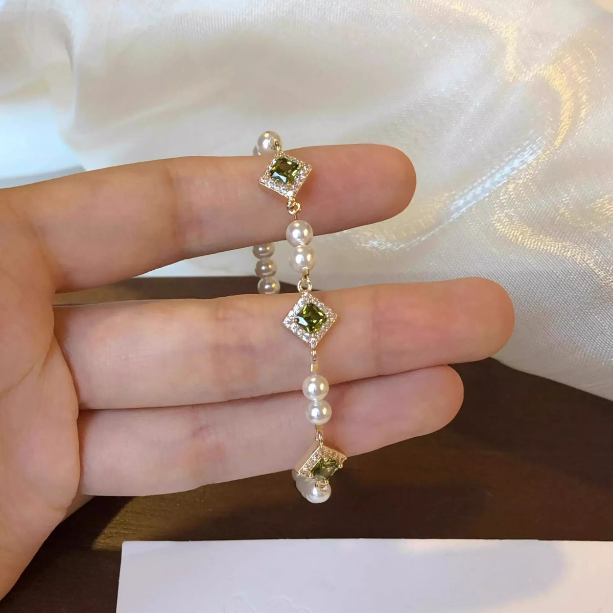Close-up of pearl beads and square zircon-set links