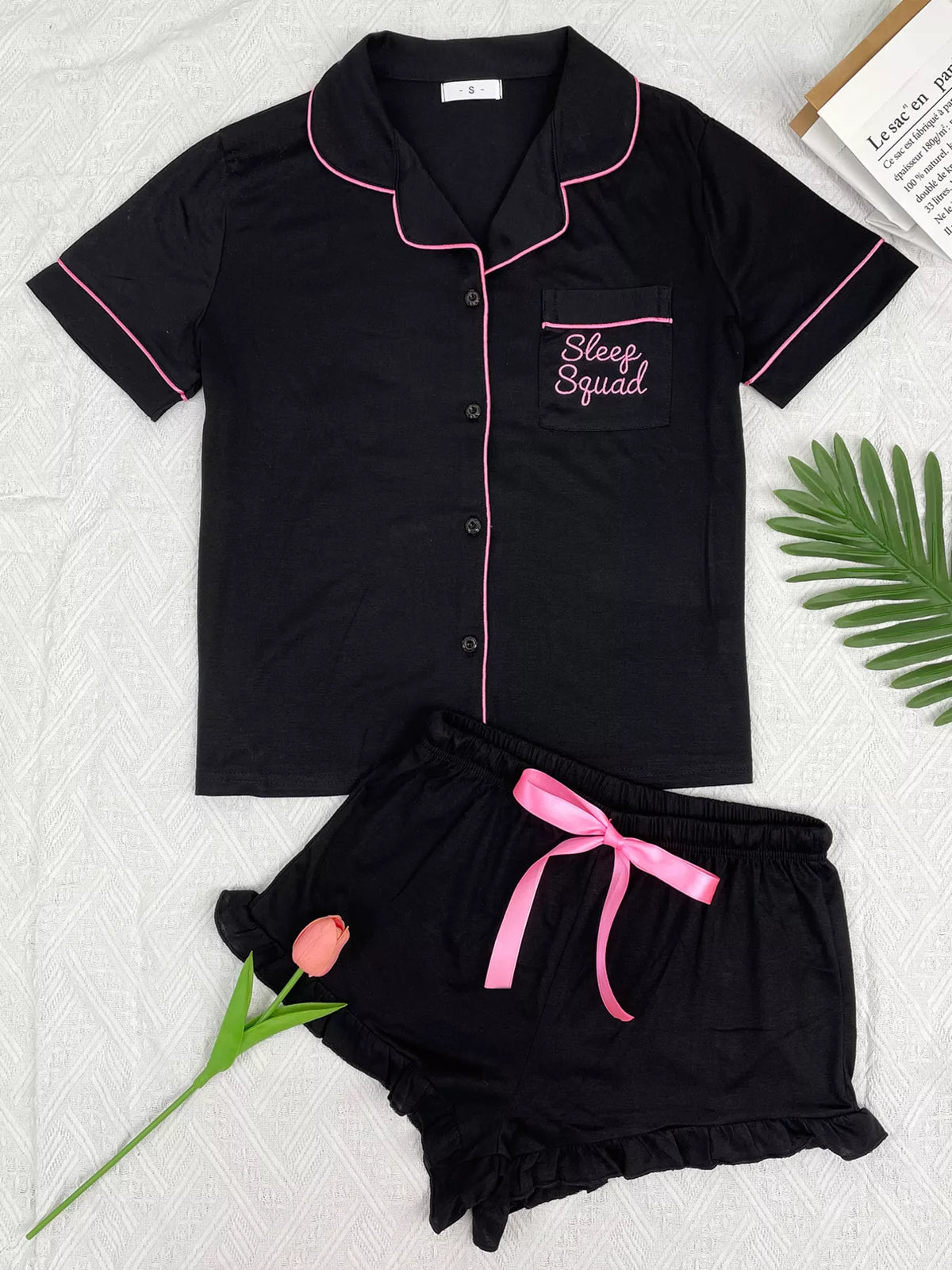 Black button-down pajama set with pink piping and matching ruffle shorts, front view
