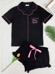Black button-down pajama set with pink piping and matching ruffle shorts, front view