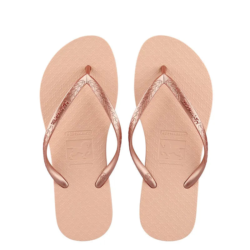 Pair of peach-coloured flip-flops with metallic rose-coloured toe-post straps, top view