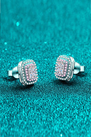 Angled view of pink-bordered rectangular stud earrings with butterfly backs on teal