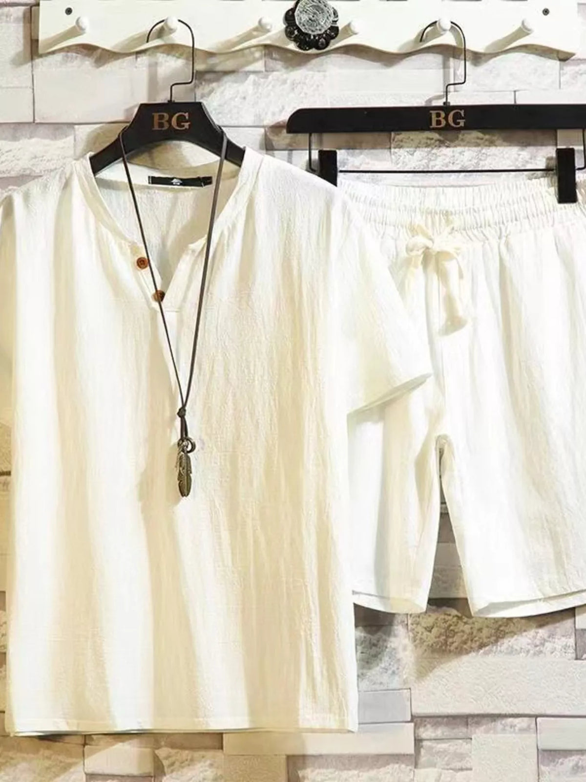 Off-white short-sleeve button-front shirt and matching drawstring shorts on hangers