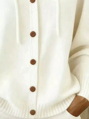 Detail of white knit cardigan ribbed hem, pockets and brown buttons