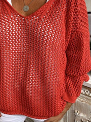 Red knit cover-up showing its loose lower front and long sleeves above white shorts.