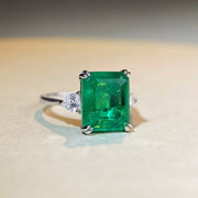 Front view of the green rectangular centre stone ring on a light surface.