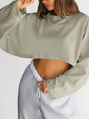 Close front view of a pale sage cropped sweatshirt worn with gray sweatpants.