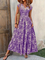 Brown floral maxi dress with a fitted smocked waist and sweeping tiered skirt, shown on a model.