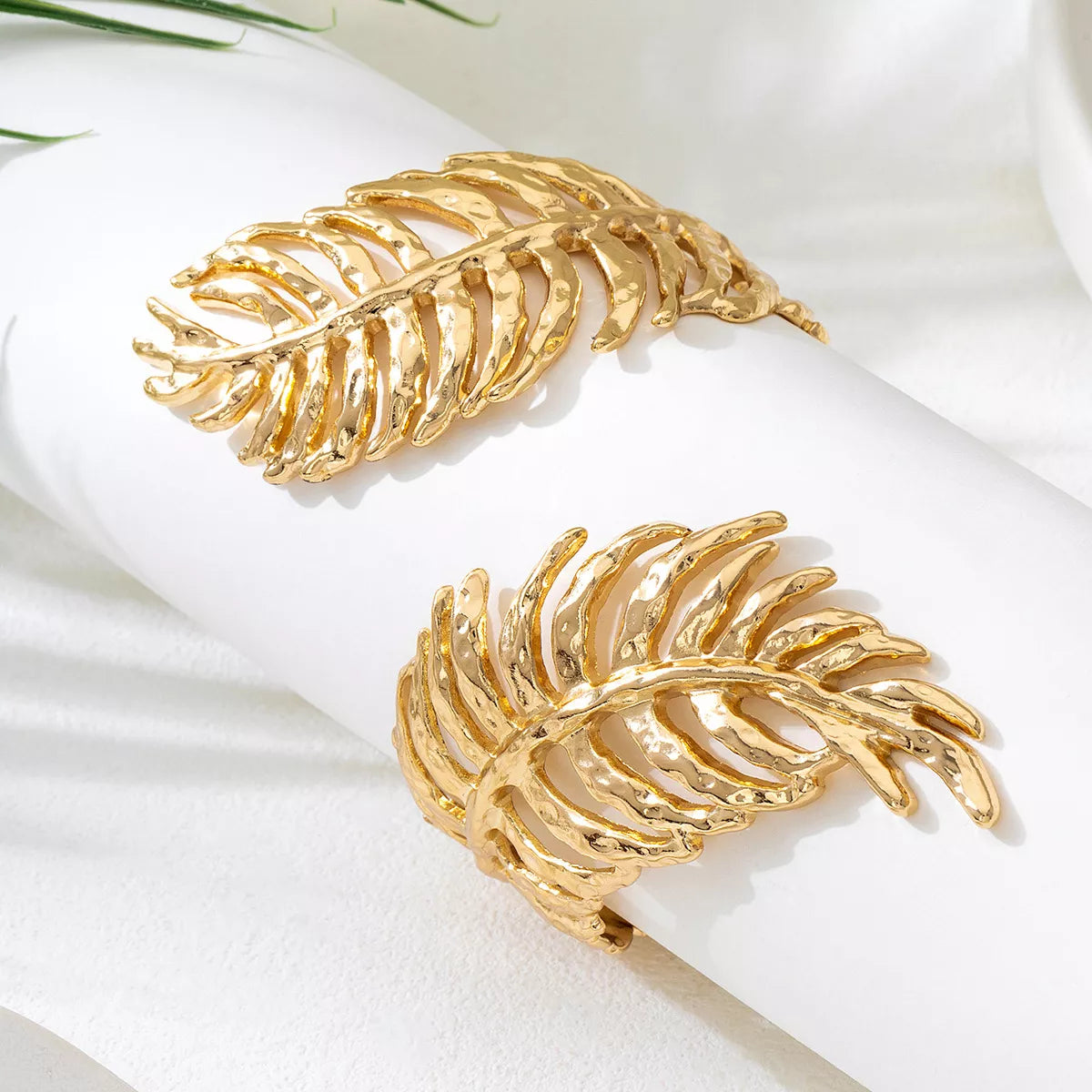 Gold-tone leaf cuff bracelet shown at an angle on light background