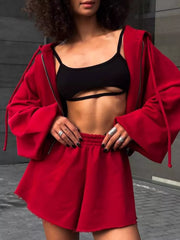 Model wearing red zip hoodie and matching shorts over a black top