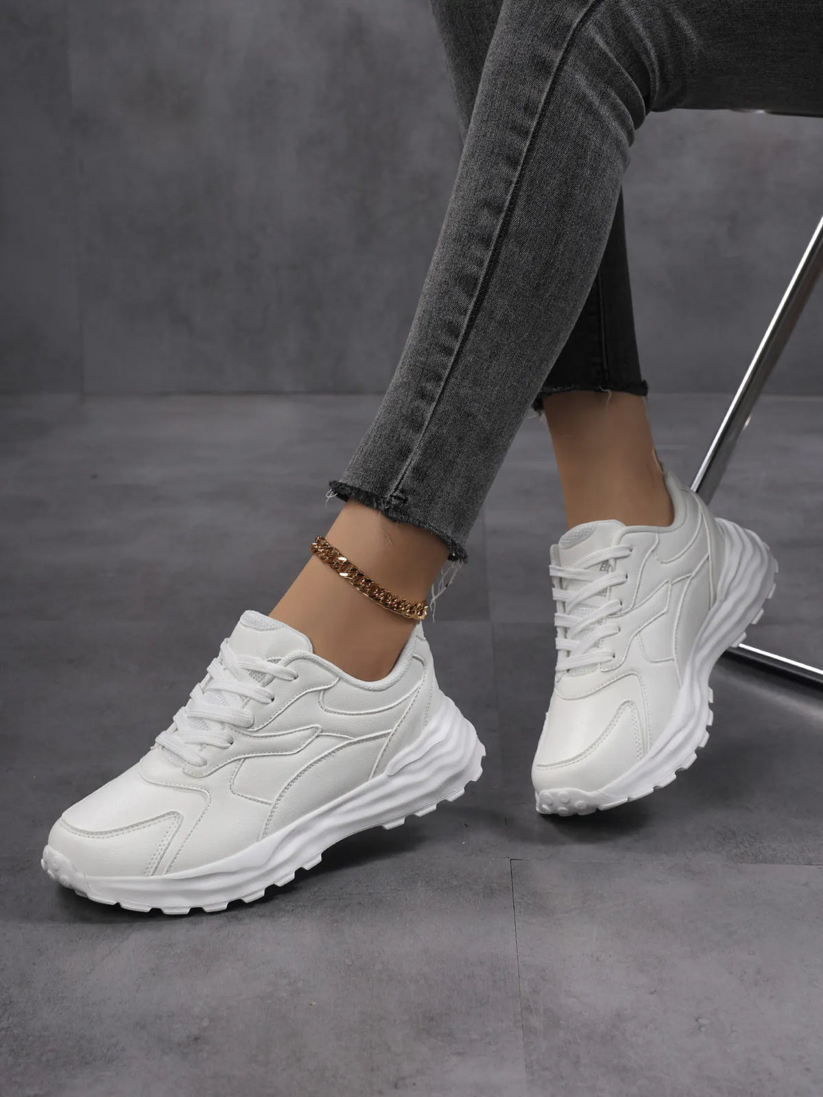 White chunky sneakers worn with jeans, angled view