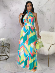 Model wearing a turquoise geometric maxi dress and holding a green handbag in a bright room.