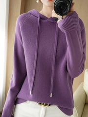 Purple hooded knit sweater shown in a front mirror photo with white trousers.
