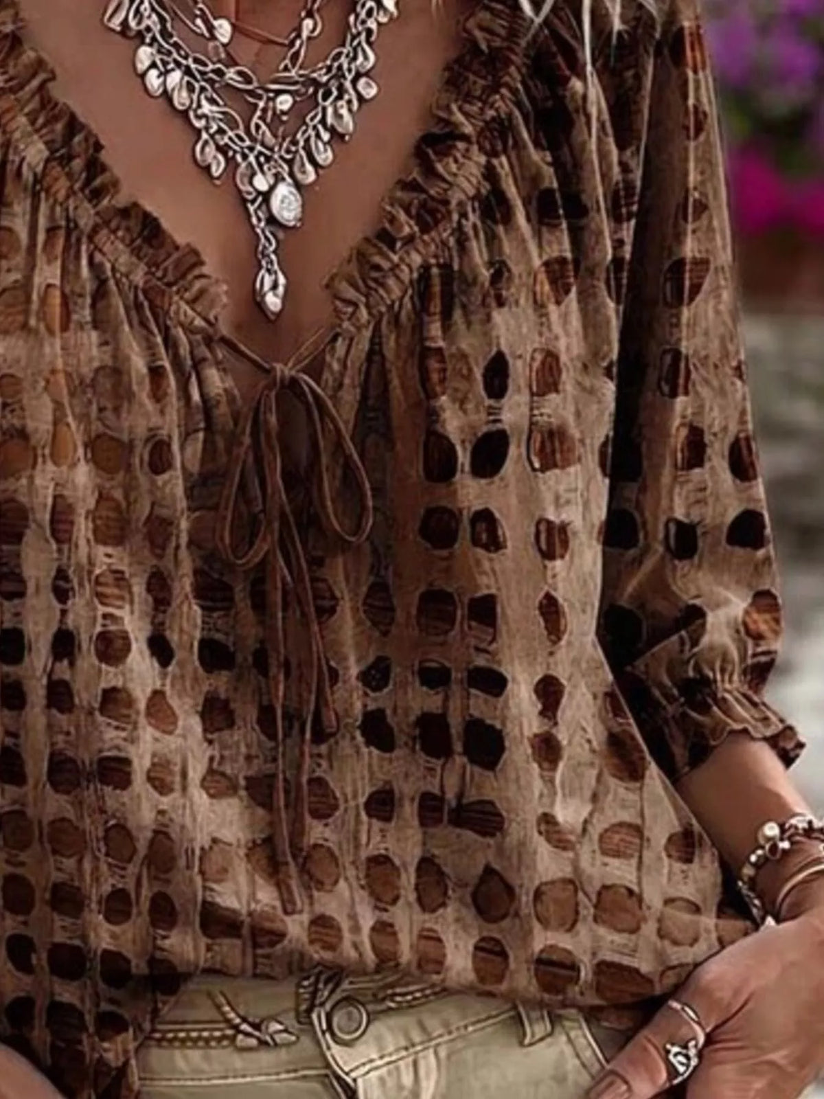 Brown printed blouse shown at an angle, highlighting its ruffled sleeve cuff.