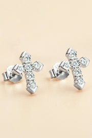 Pair of sparkling cross-shaped stud earrings arranged on a warm beige background