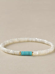 Side view of the turquoise accent beads and gold-tone spacers on a white bracelet