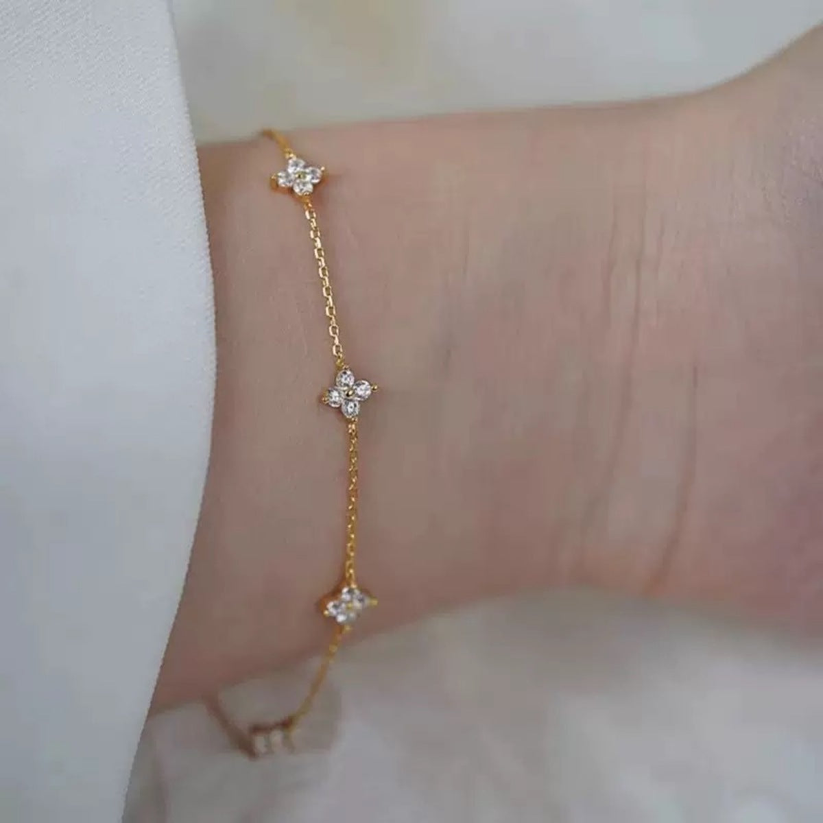 Gold-tone clover bracelet worn loosely around wrist