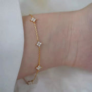 Gold-tone clover bracelet worn loosely around wrist