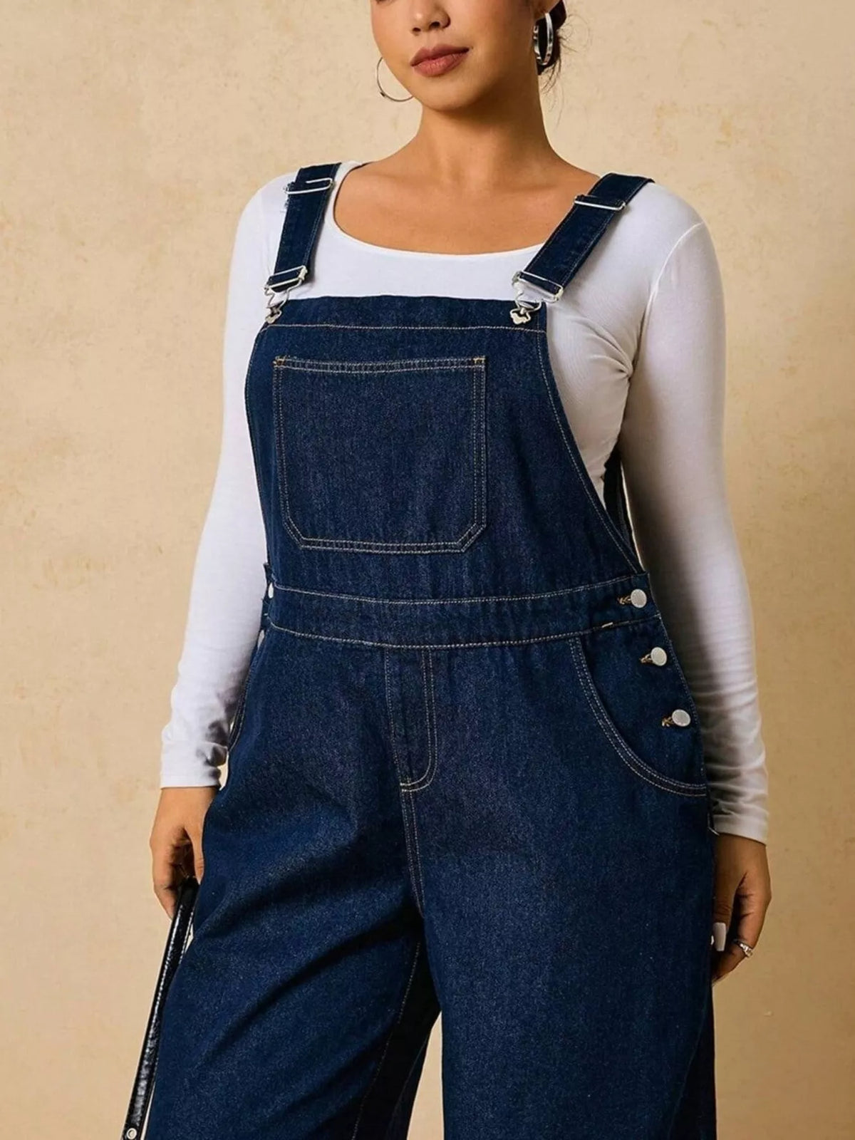 Close-up of the dark blue overalls' adjustable buckles, bib pocket and side buttons.