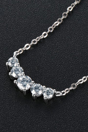 Close-up of clear stones along curved silver necklace on black background